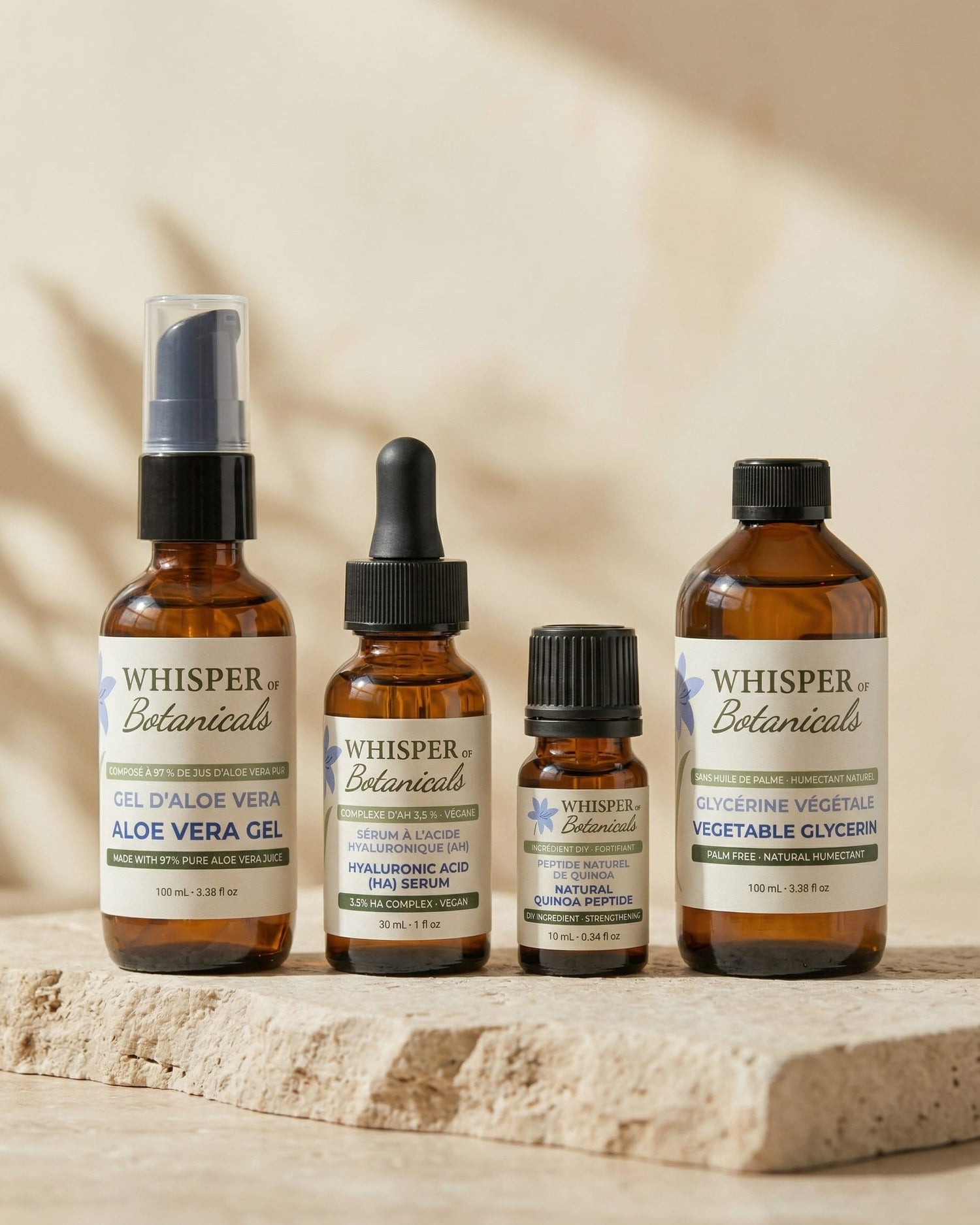 Four bottles of Whisper Botanicals products on a stone surface with a neutral background.